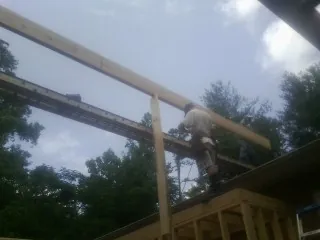 Carpenter setting a ridge beam over a new addition frame — Ice Dam Removal by Roofing Brothers in Ratliff City