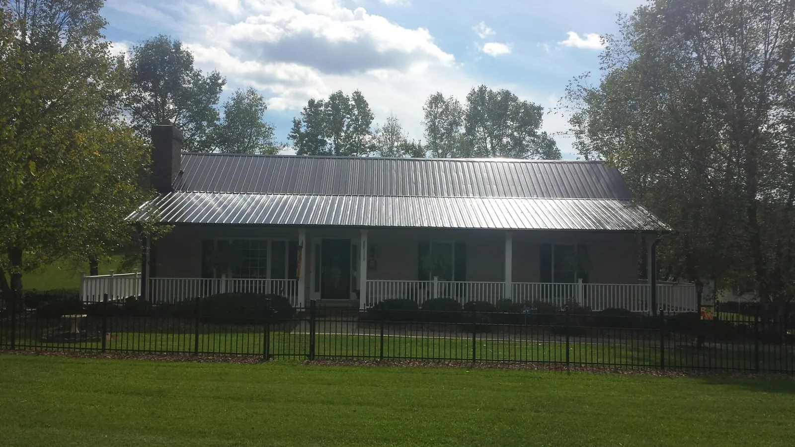 Gray metal roof on a brick ranch with a full width front porch — Gutter Guard Installation work by our crew in Ratliff City