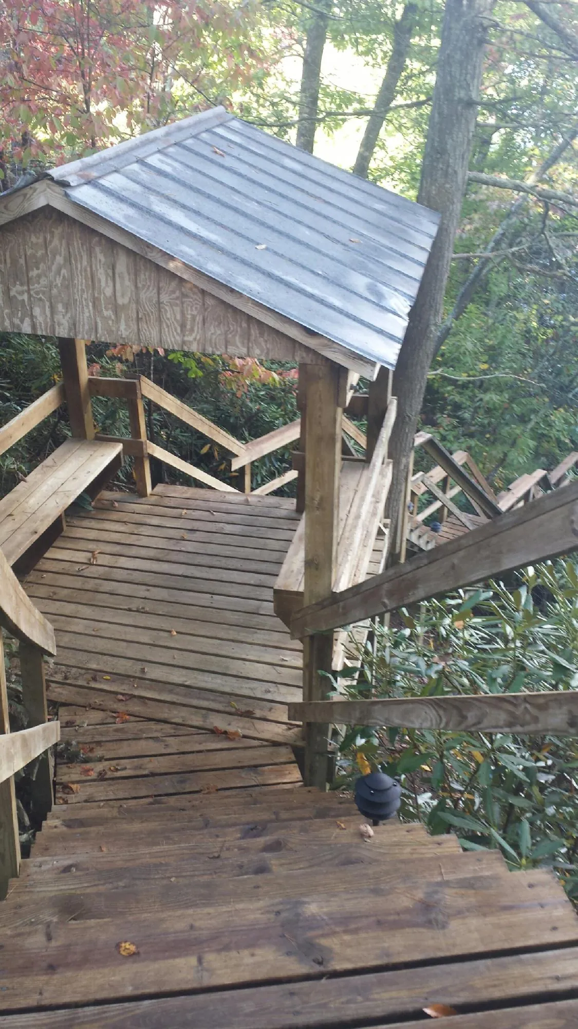 Metal roofed shelter over wooden steps on a wooded walkway — Skylight Repair & Installation work by our crew in Ratliff City