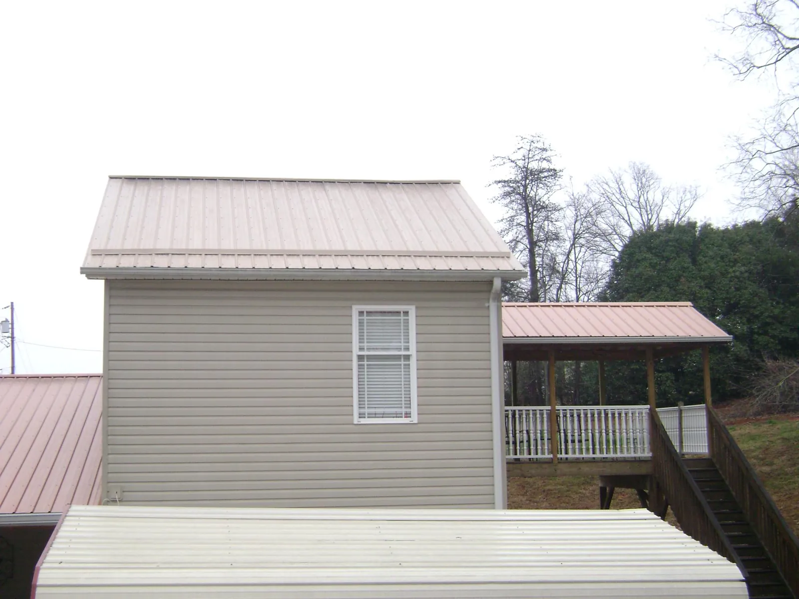 Tan metal roofs on a two story addition and attached porch, from a Roof Replacement job in Ratliff City