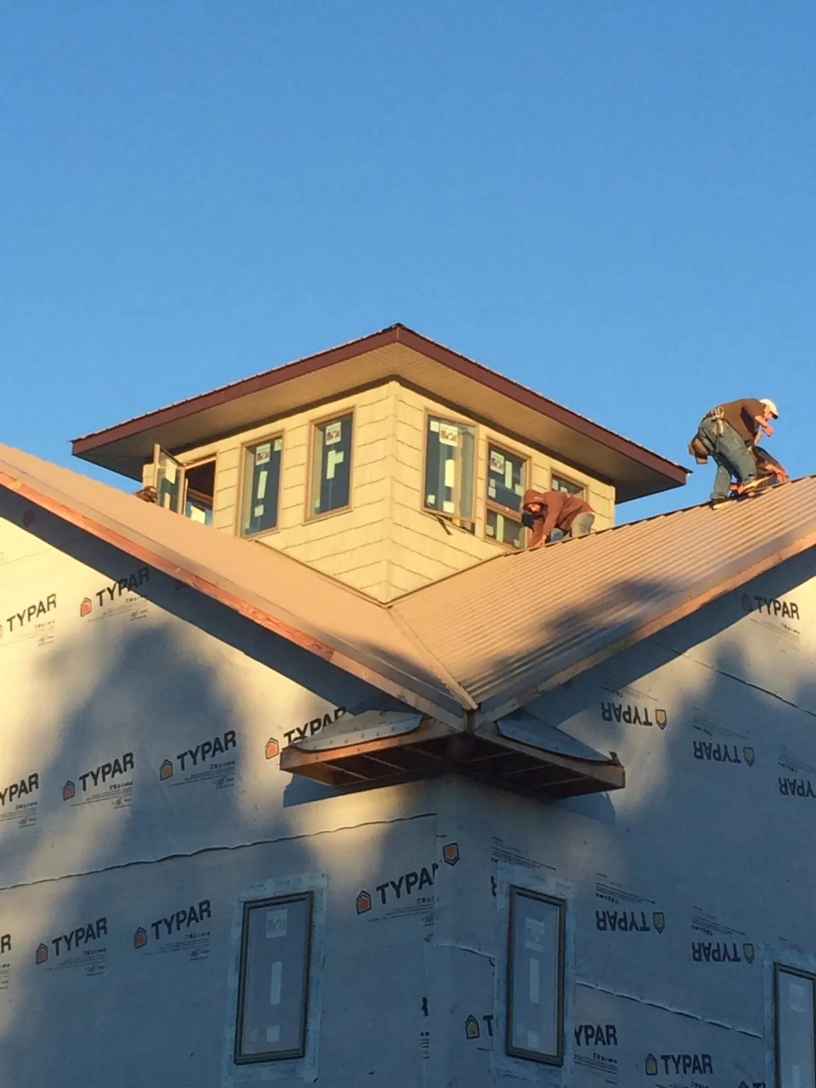 Roofers working around a rooftop cupola on a new metal roof at sunset — Roof Waterproofing in Ratliff City by Roofing Brothers